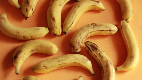 ripe delicious wet bananas rotate clockwise on a black plate on a yellow background