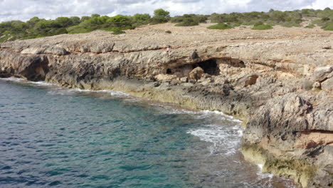 AERIAL:-Tropical-Island-Rock-Coast-with-Jungle-Forest-in-the-background-Sunny-Weather,-Sunshine