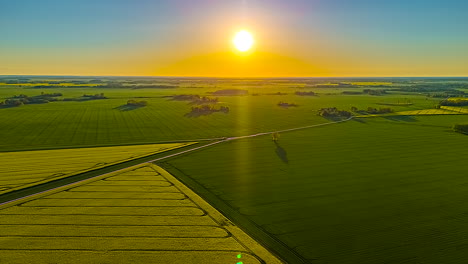 aerial hyperlapse of sun over farmlands with roads and trees during golden hour