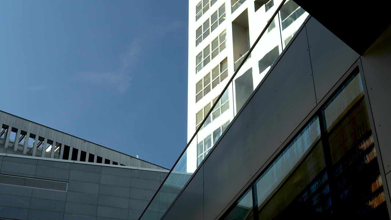 mirando hacia un edificio moderno de gran altura que se cruza con otra estructura contra un cielo azul