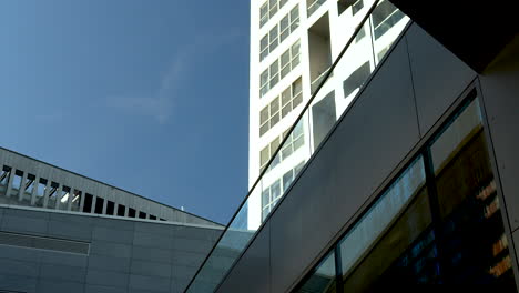 looking up at a modern high-rise building intersecting with another structure against a blue sky