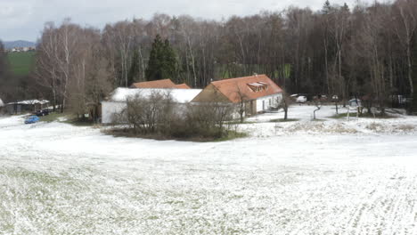 Casa-De-Campo-Con-Campos-Nevados-Y-árboles-Sin-Hojas-En-El-Campo-De-Invierno