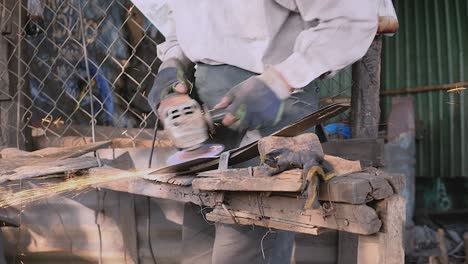 worker sharpening a broad blade with a grinding wheel