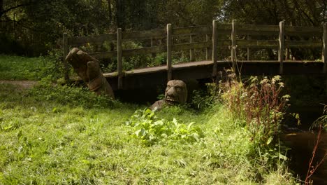 mid shot of wooden bridge over scow brook with carved wooden troll man at bridge base