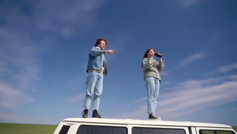 un jeune garçon et une jeune fille regardent autour d'eux avec une paire de jumelles sur le toit d'une caravane