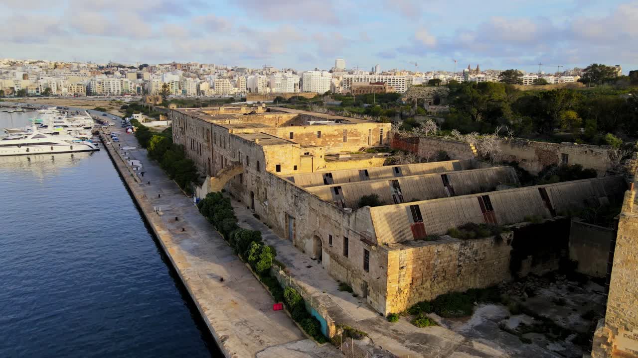 Vista aerea con drone degli edifici abbandonati del Lazzaretto lungo il porto di Marsamxett con porto turistico e skyline della città a Malta