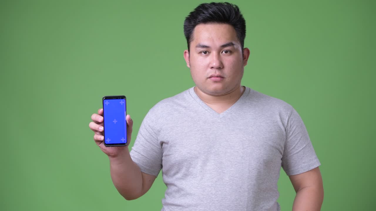 초록색 배경에 젊은 잘생긴 과체중 아시아인