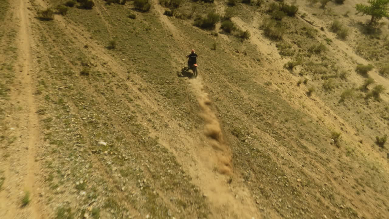 maniobras de motociclista en la colina descuidada en motocross fpv. moto deportista monta motocicleta en las tierras altas del desierto en un día de verano. explorar área virgen en vehículo