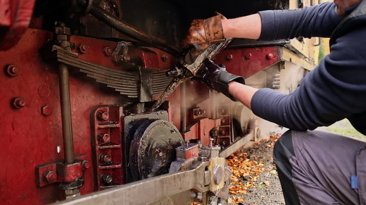 Mechanic adding oil in mechanisms of the stopped steam train Mocanita on a railway station in Romania. Slow motion