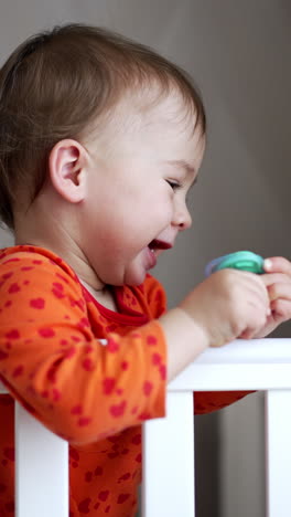 adorable newborn boy playing with a grib. cute kid standing on the bed. vertical video