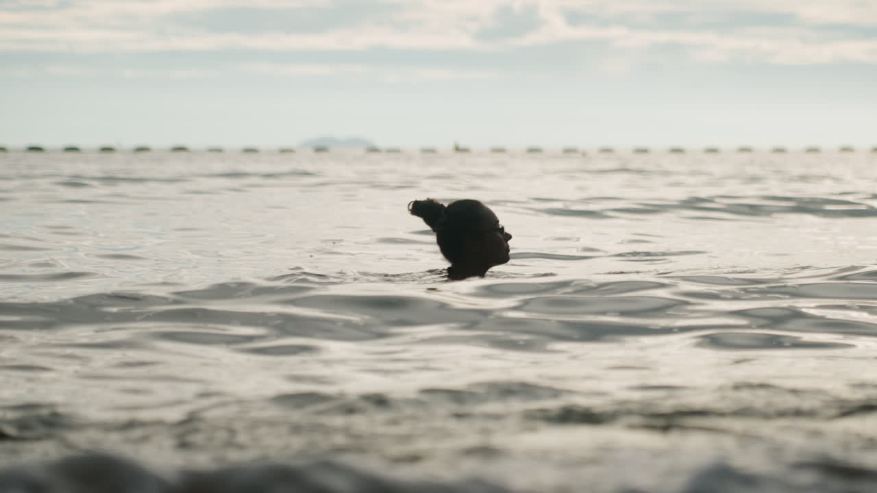 Black woman swimming with green ball in open ocean, playful retrieve and splash against gentle waves energetic beach game, active leisure, candid motion and summer vibe with horizon line and coastal