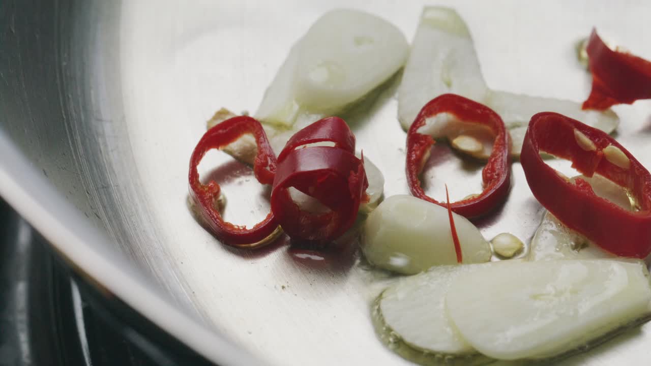 Slices of Garlic and Red Chili Frying in Oil in Steel Pan