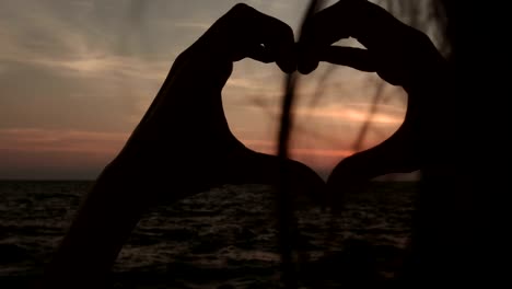 woman making heart shape sign with hands at sunset girl holding up love symbol