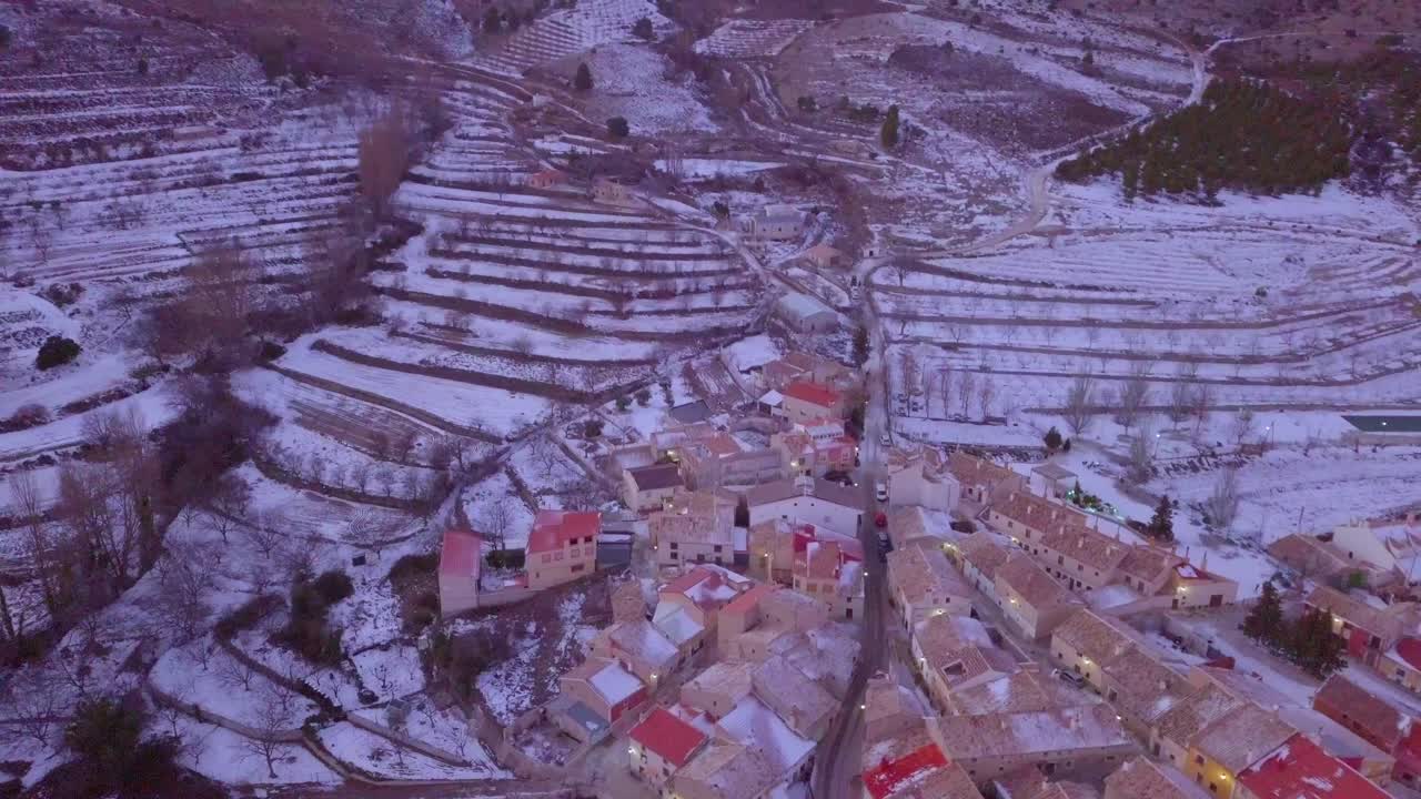 눈으로 뒤덮인 스페인 마을과 함께 높은 산을 패닝하는 드론