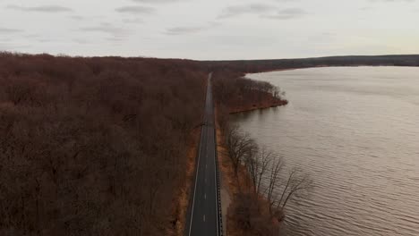 drone-aerial-over-a-road-in-bare-forest-trees-in-autumn-4k