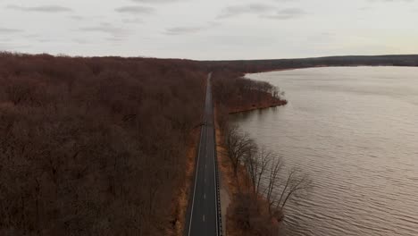 avión teledirigido sobre una carretera entre árboles forestales desnudos en otoño 4k