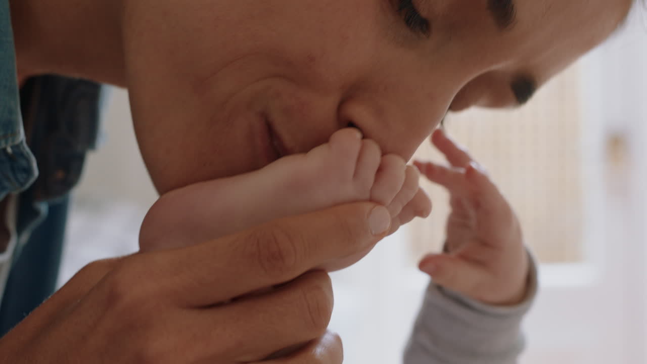 close up mother kissing baby's feet playfully nurturing newborn caring for infant enjoying motherhood connection with child