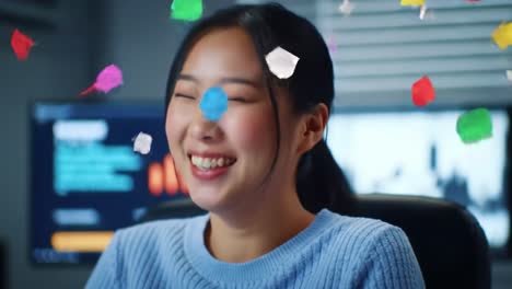joyful moments captured: a young woman's delight as colorful confetti falls around her while engaged in a lighthearted activity at her workspace