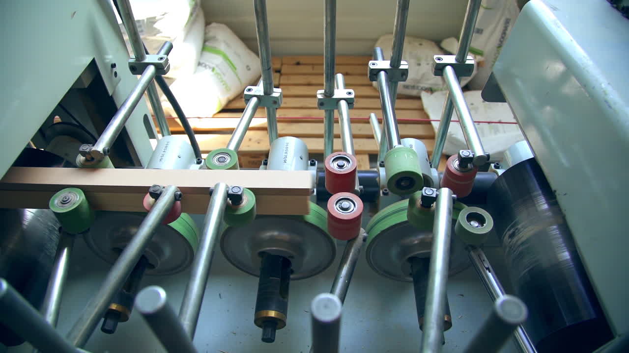 Equipment with numerous rotating rollers. Metal beams moving quickly by the machine. Top view.