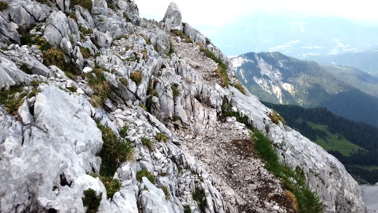 punto de vista de caminar por un sendero alpino alto expuesto en alemania, que conduce a una curva, con cielo azul y valle profundo