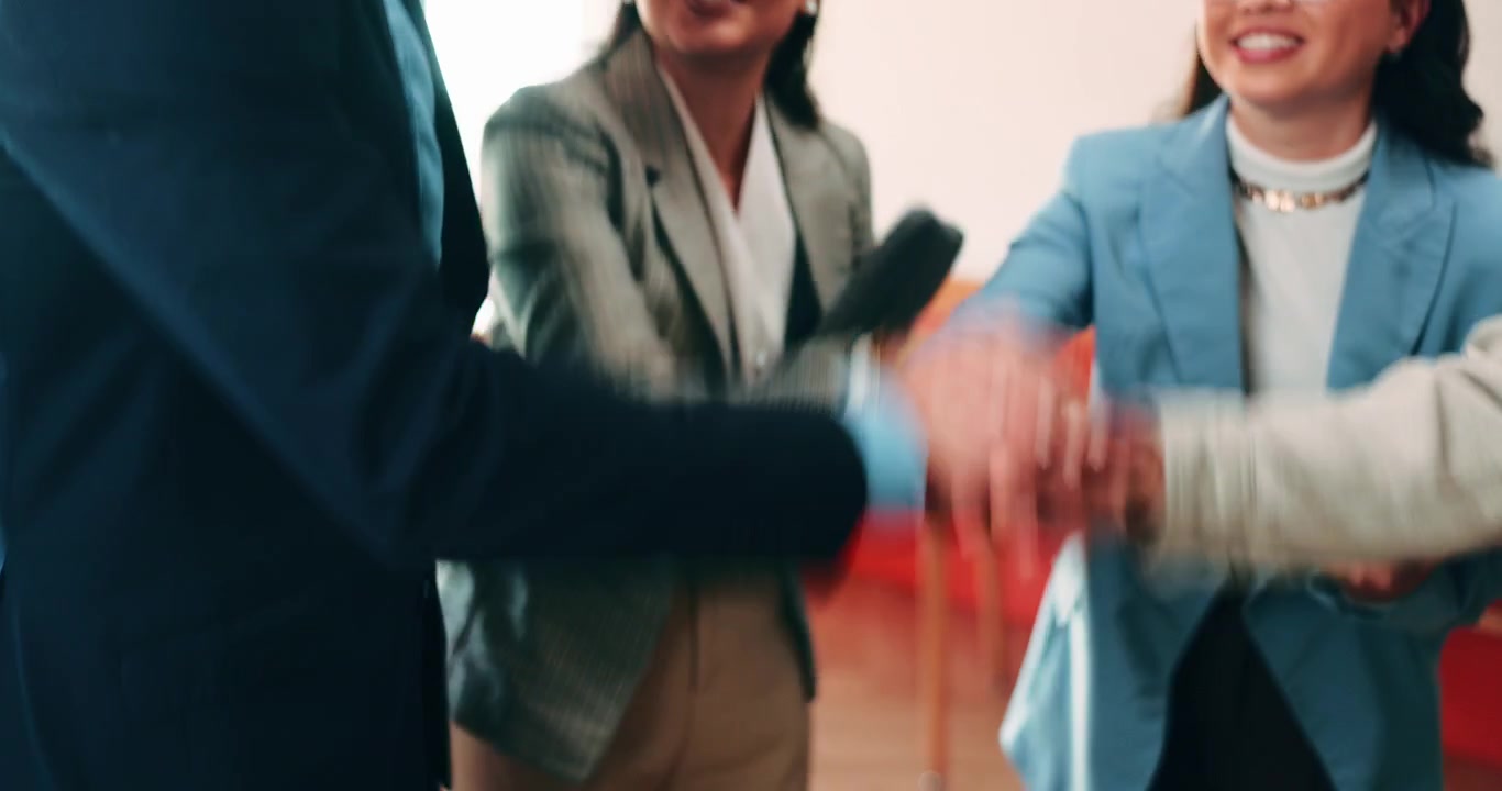 Forretningsteam der lægger hænder oven på hinanden og fejrer succes på kontoret