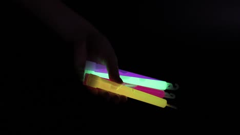 a hand holding multiple colorful glow sticks