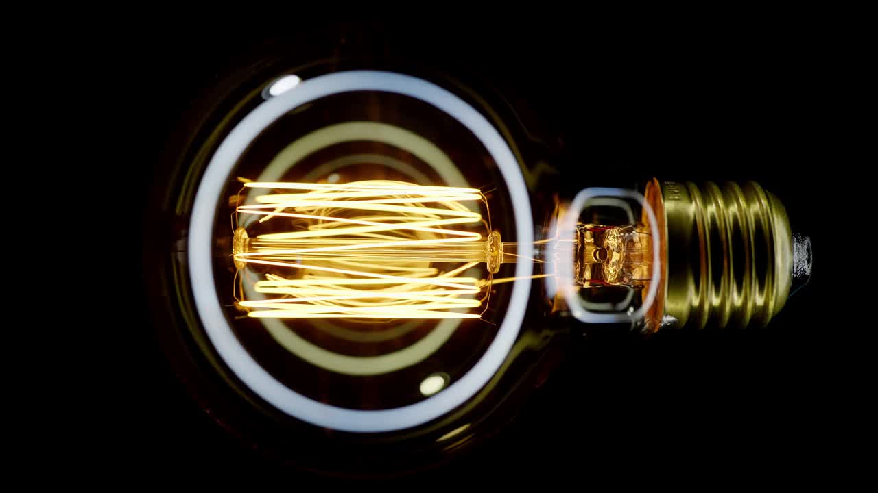 una bombilla de tungsteno parpadeando sobre un fondo negro.