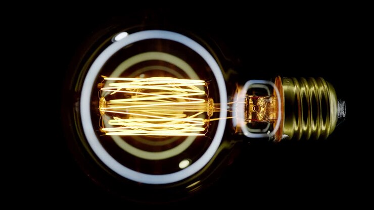Tungsten light bulb blinking over black background.