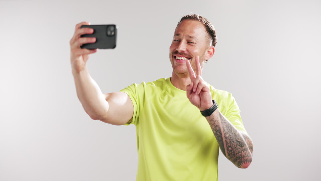 Uomo felice che si scatta un selfie e fa gesti con le mani in studio