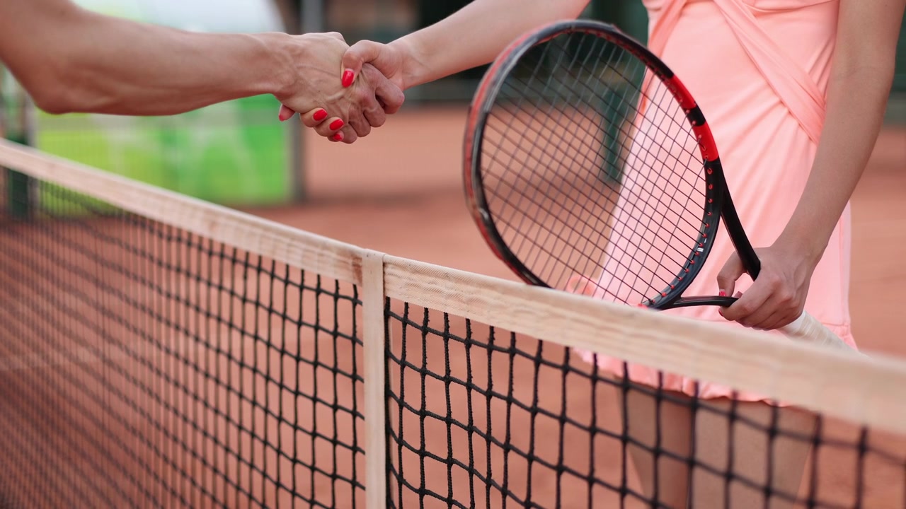 Tennis Players Shaking Hands Over the Net on a Clay Court