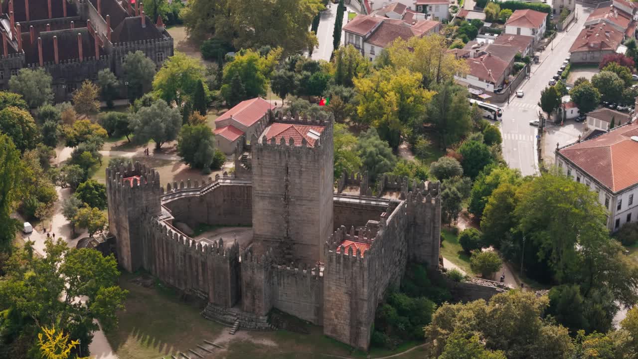 aerial Pan Guimarães castle with portuguese flag waving proudly above fortress
