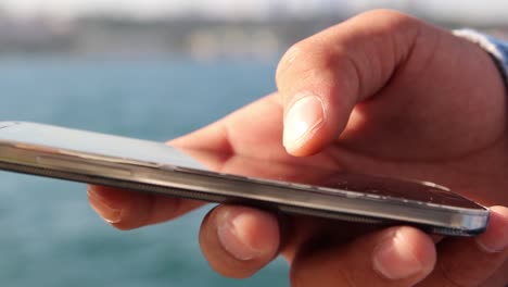 Close-Up-Shot-Of-Man'S-Hands-With-Mobile-Phone-On-Background-Sea-View