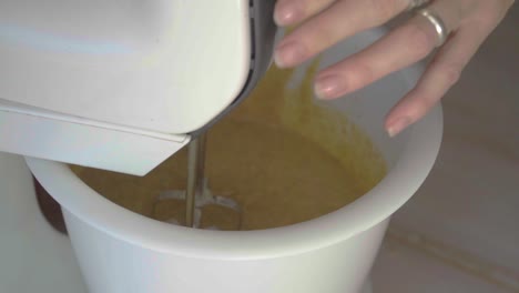 high-angle, slow-motion view of a mixer coming to a stop while preparing a batter