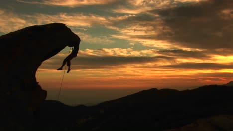 plano médio de um alpinista em silhueta pelo sol poente da califórnia