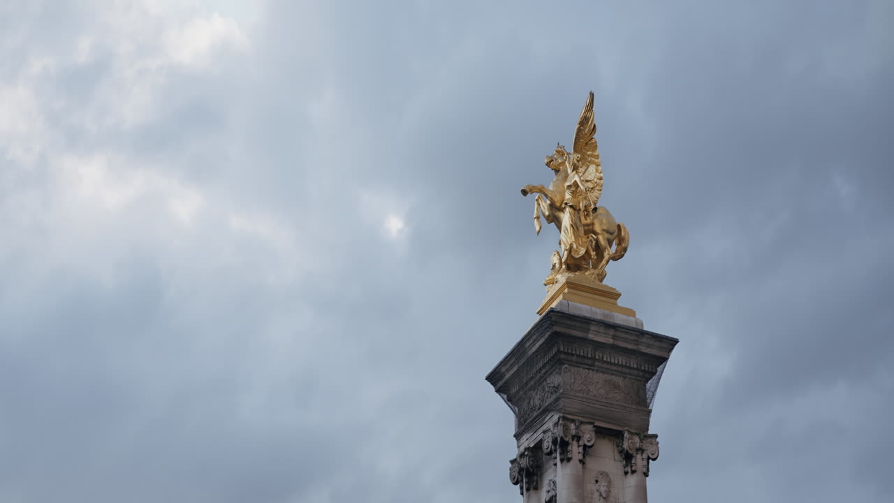 Golden Statue of an Angel on a Column against a Cloudy Sky