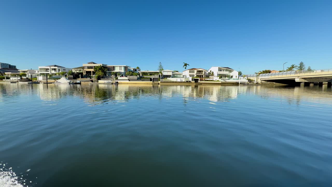 Campo lungo da una barca in movimento che riprende lussuose ville moderne lungo un tranquillo canale fluviale
