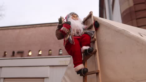 babbo natale giocattolo che si arrampica sul tetto di un edificio su una scala al festivo mercato di natale a strasburgo, francia europa