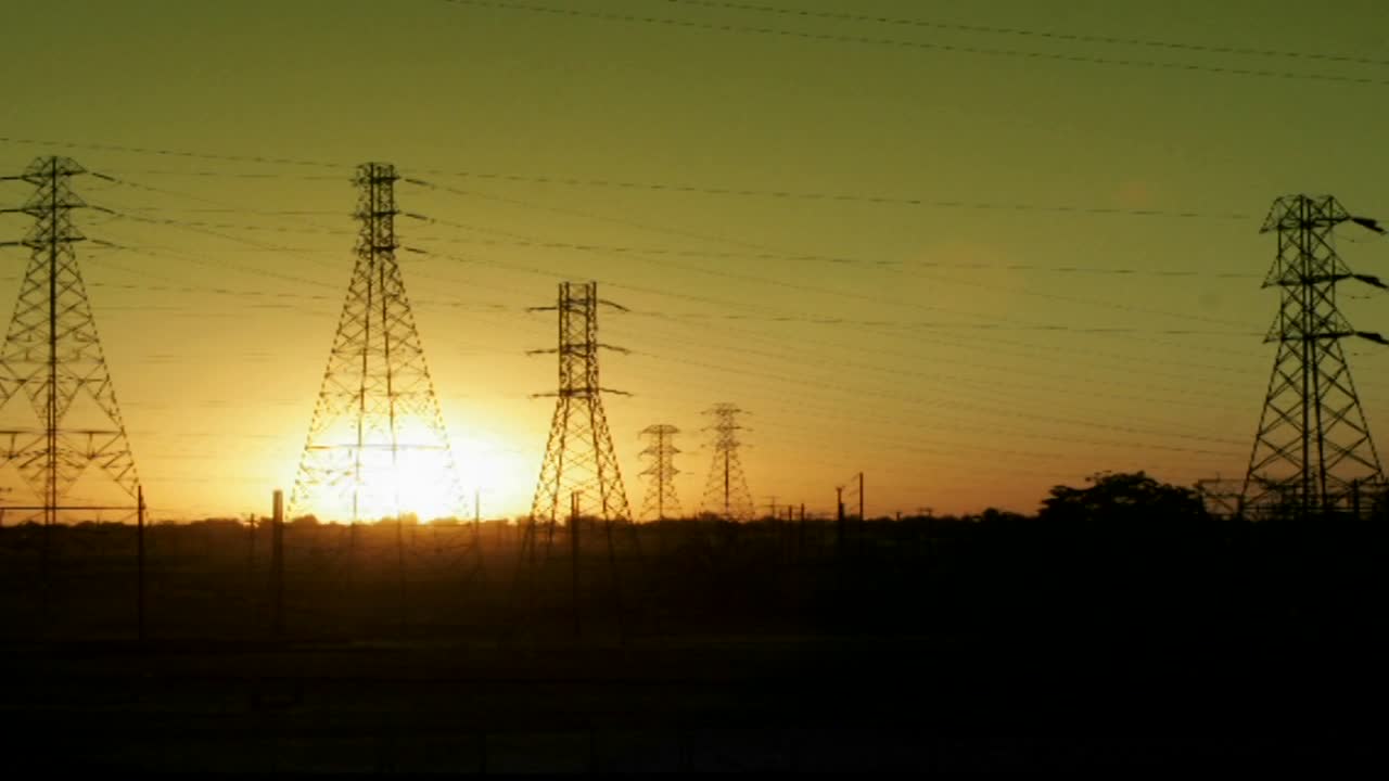 The sun sets behind high tension lines in this time lapse shot