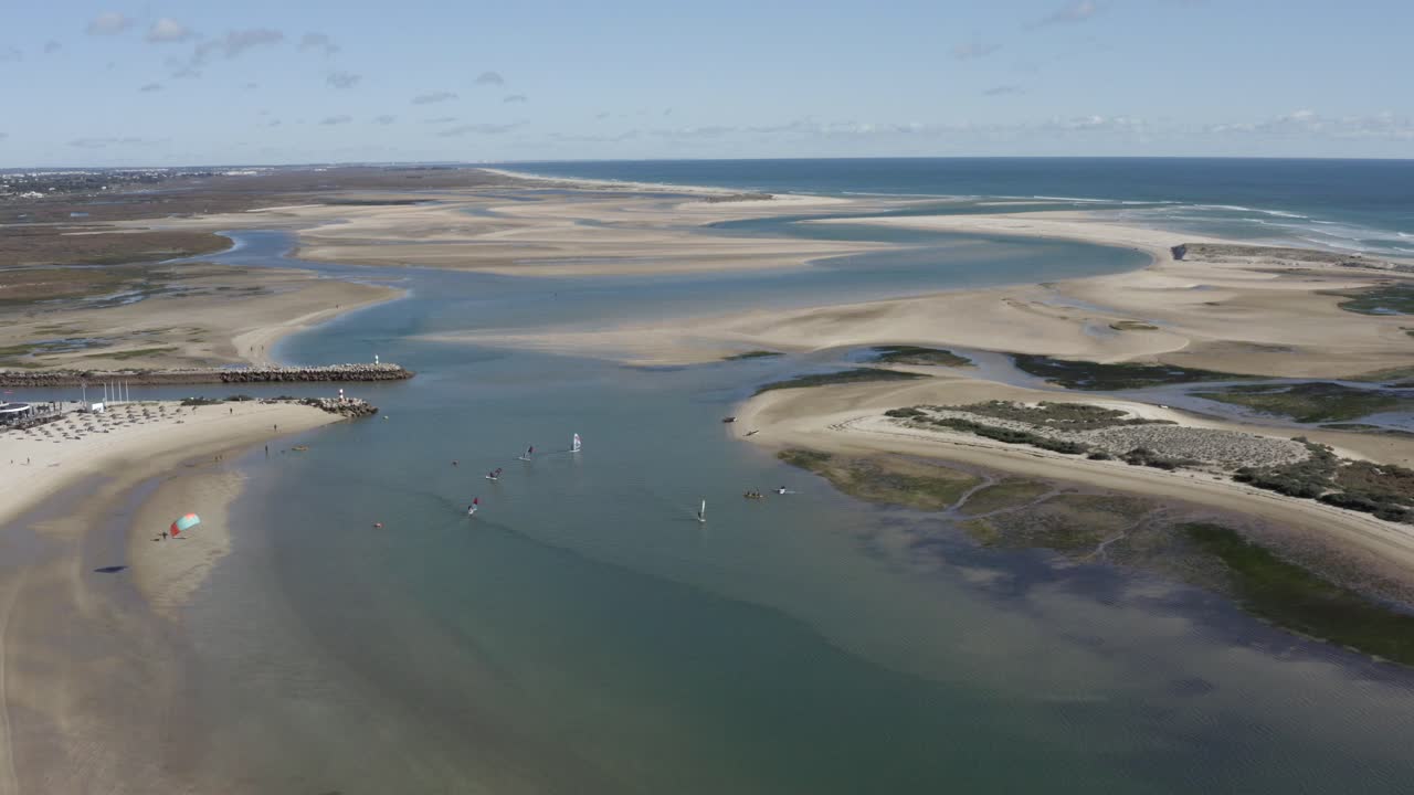 windsurfistas y navegantes disfrutando de buenos vientos en una playa de fuseta, portugal