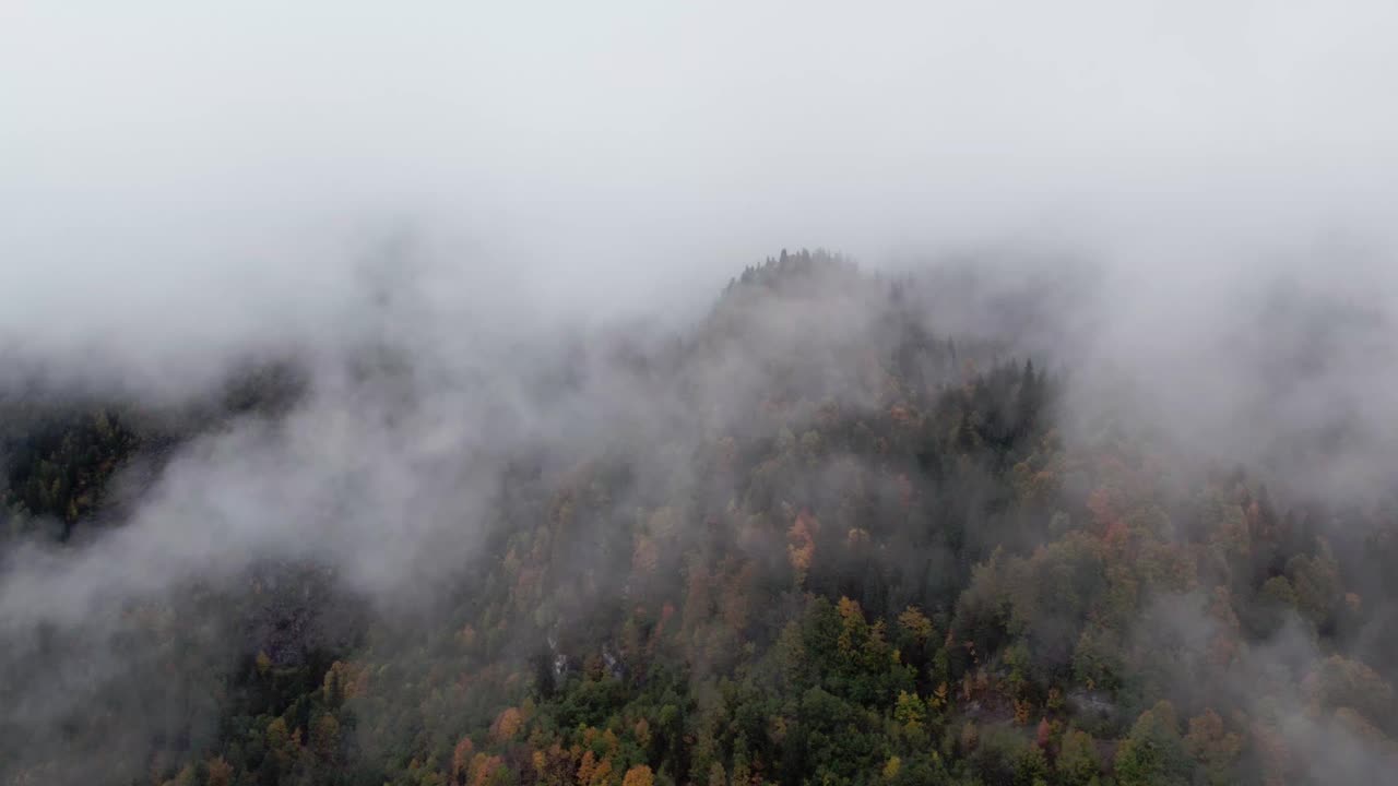 Aerial view of a mountain emerging from the clouds, its tapered peaks barely visible in the mist.