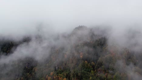 aerial view of a mountain emerging from the clouds, its tapered peaks barely visible in the mist.
