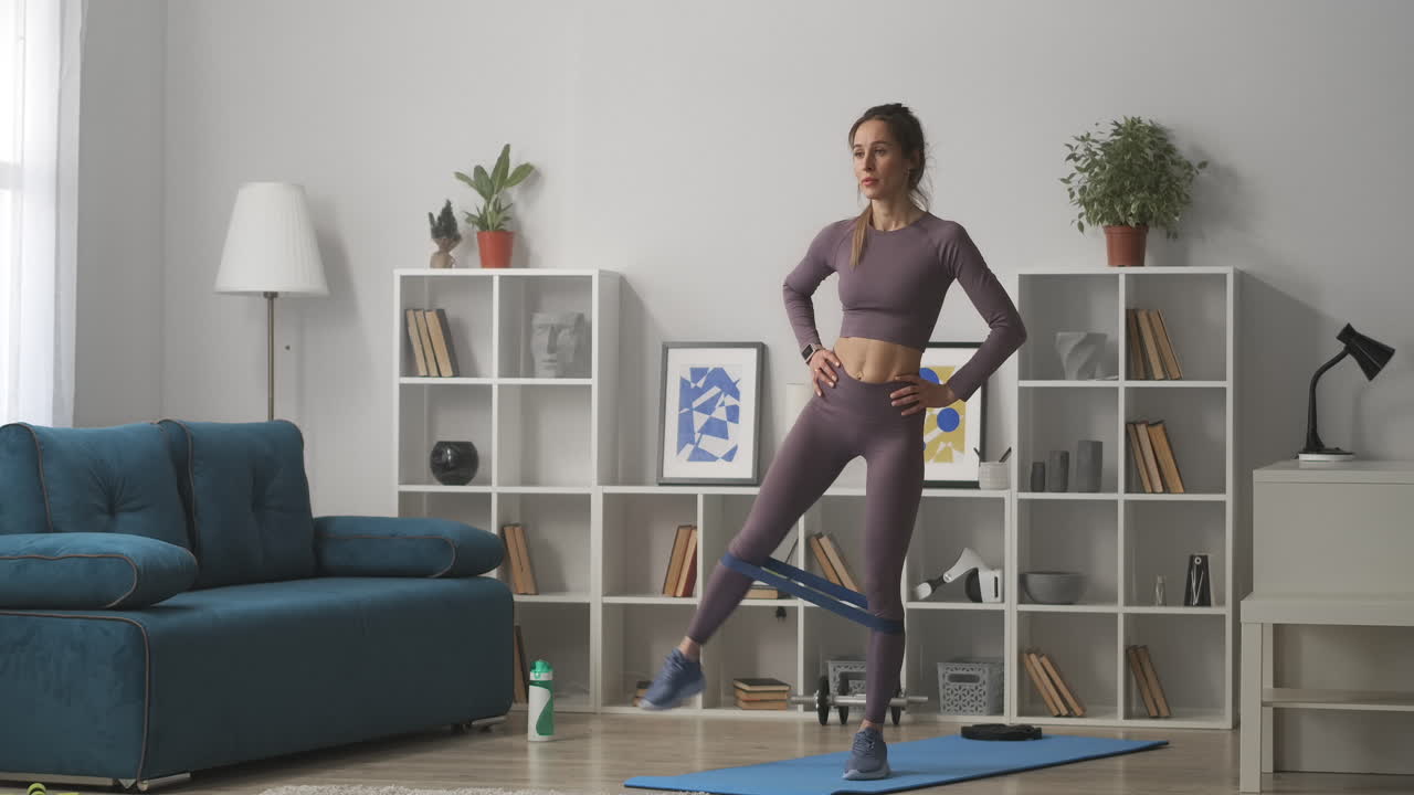 entrenamiento de aeróbicos y gimnasia en casa mujer está moviendo las piernas de pie en la sala de estar cuerpo femenino deportivo vestido ropa deportiva de moda estilo de vida saludable