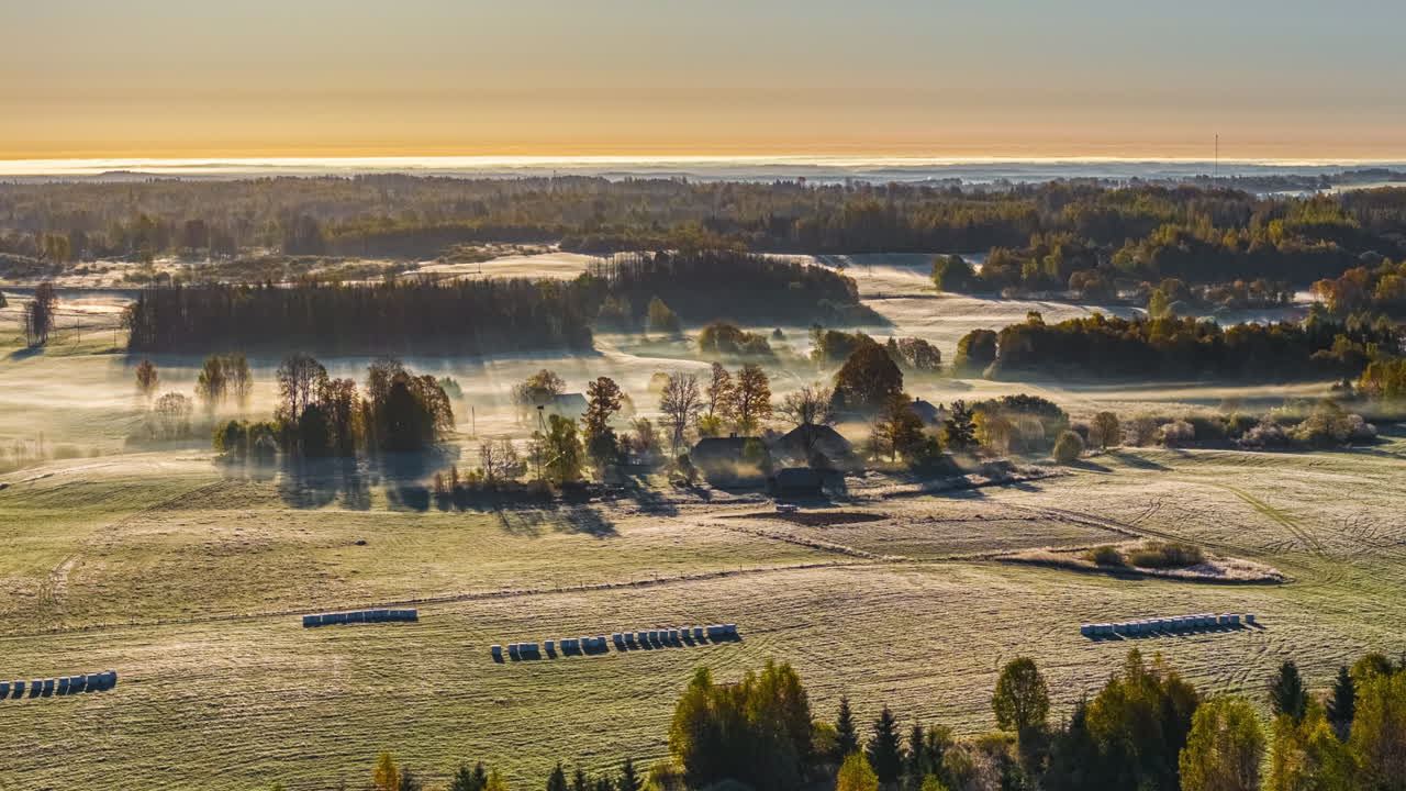 Morning Sunlight Spreads Across Misty Fields and Forests, Creating a Peaceful Golden Landscape - Static Wide Shot
