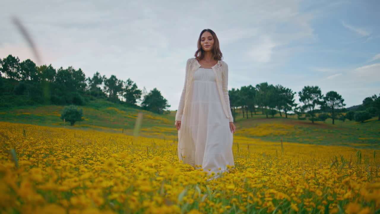 Relaxed model strolling flowers field. Lady white dress looking camera walking