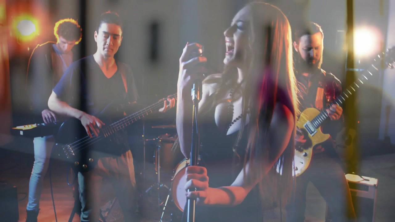 Video verticale: Luci che attivano un effetto flare in sovrapposizione sul cantante solista che canta nel microfono, con la band che suona la musica.
