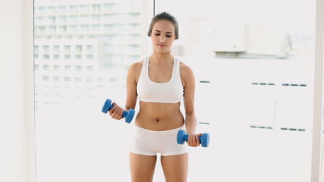 fit young woman lifting dumbbells and laughing