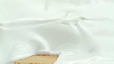 wafer candy bar falling into creamy milk making splash in macro and slow motion