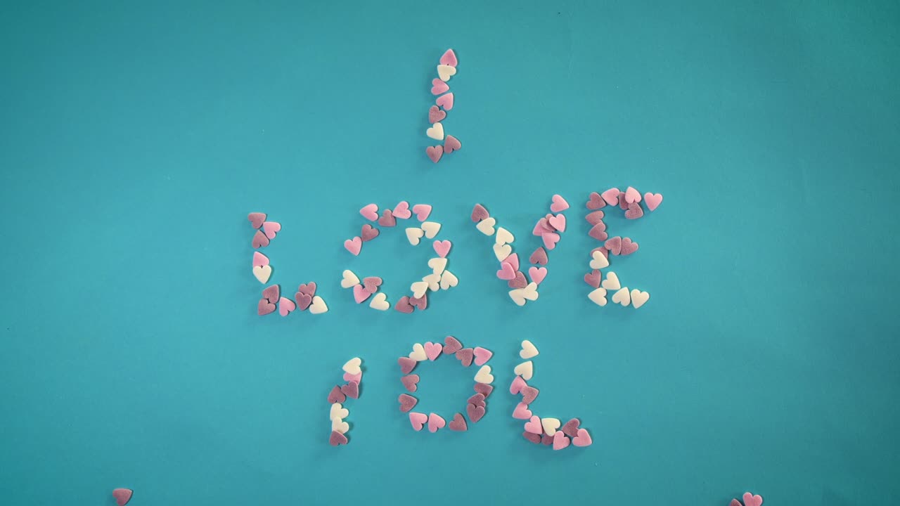 심장 모양의 사탕을 가진 스 모션 애니메이션이 사랑이라는 단어를 만니다.