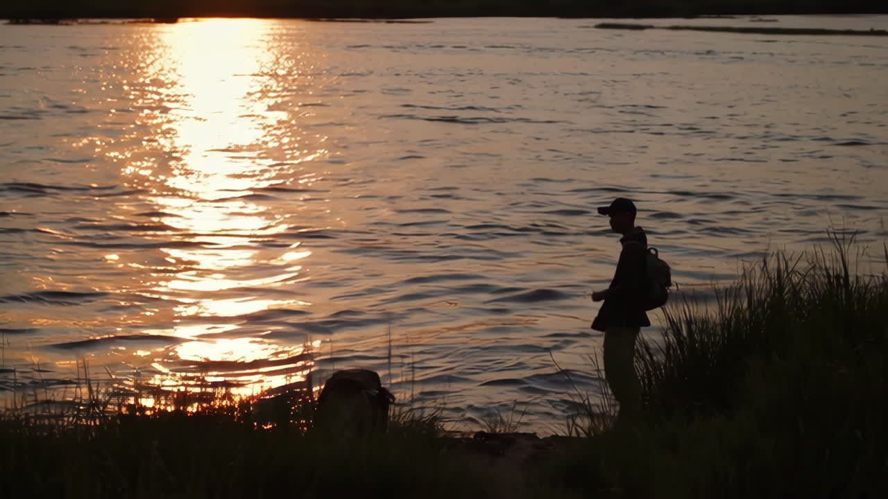 Silhouette of Person by a River at Sunset