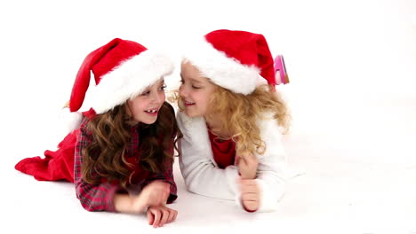 Cute-festive-girls-lying-on-floor-telling-secrets